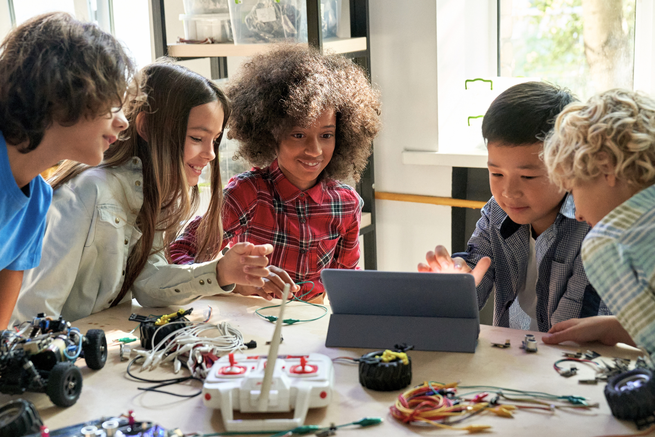 A diverse group of middle school students works collaboratively together on a robotics project