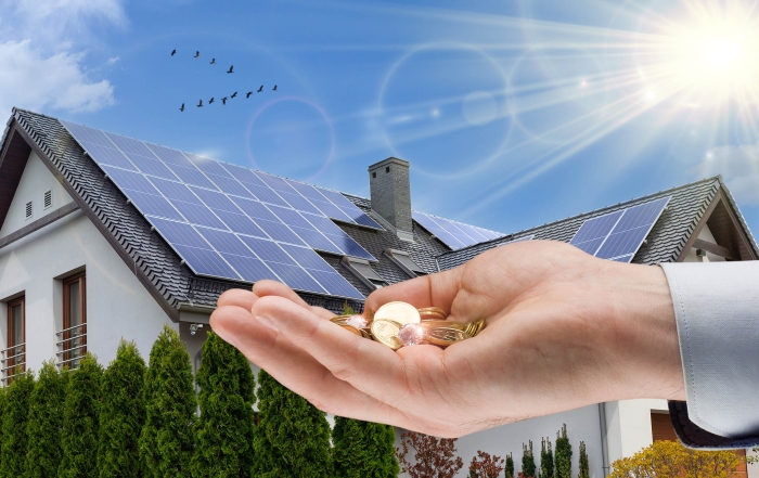 hand holding coins, solar panels on roof of a house, sunshine